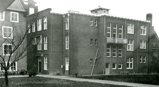 F000528-1 Achterzijde en doorgang naar de binnenplaats van de ziekenzaal van de Gast- en Proveniershuizen uit 1930, ...
