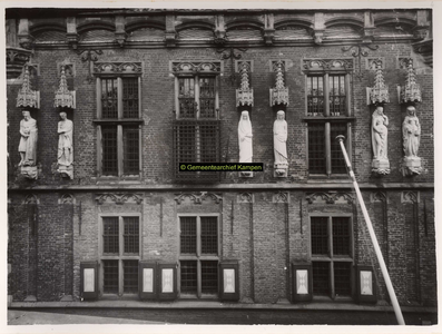 F001364 Beelden en laat-gotische ijzeren kooi aan de gevel van het Oude Raadhuis in de Oudestraat, v.l.n.r. Karel de ...