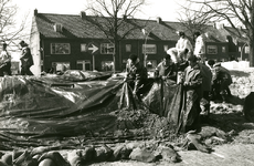 F008037 Bij de nooddijk aan de IJsseldijk worden de zandzakken afgedekt met plastic.