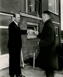 F011498 De sleutel van de modelwoning word overhandigd door A.K. Versteeg, directeur Gemeentewerken, aan burgemeester ...