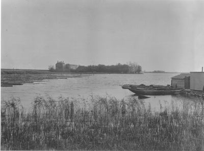 Foto van de binnenzijde van de Diemerzeedijk met het Gemeenlandshuis en een bootje in Nieuwe Diep, 1921