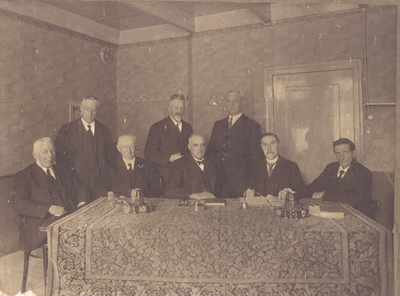  Foto van 8 leden van bestuur van Ronde Hoeppolder met hamer, bel en notulenboeken, ca. 1930