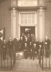  Foto van het bestuur hoogheemraadschap Zeeburg en Diemerdijk bij de deur aan de voorzijde van het Gemeenlandshuis