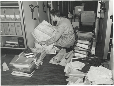 FOTO-001828 Binnenkomst polderarchieven: archivist dhr. Sloof bekijkt de archiefstukken in de kluis, 1983
