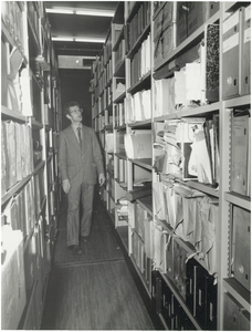 FOTO-001829 Binnenkomst polderarchieven: archivist dhr. Sloof tussen de stellingen in de kluis, 1983