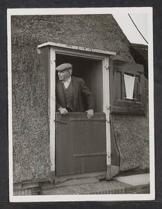 FOTO-700615 Molenaar Jan Spruitenburg met pet op in de half geopende deuropening van de Steektermolen, september 1956