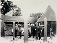 7536 Handboogschieten door enkele militairen en burgemeester (rechts) Baken nabij het gemeentehuis (op achtergrond), ca. 1915