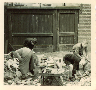 501162 Schooljeugd bij het opruimen van stookhout, 1957