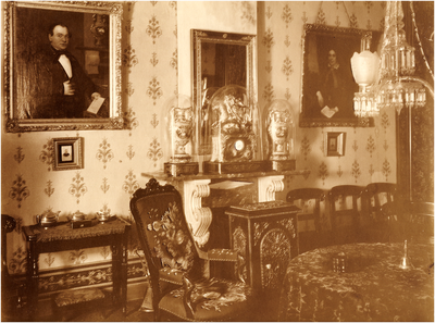 180941 Woonkamer in het huis van de familie Coovels-Bots met aan de muur het portret van Gerardus J. Coovels en rechts ...