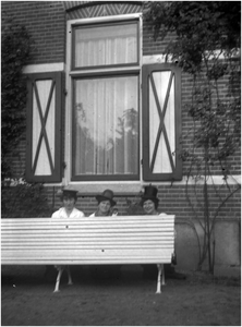 182204 V.l.n.r. Adèle de Charro, Jo Coovels en Paula Coovels zitten met hoedje op achter een bank voor het huis van Jo, ...