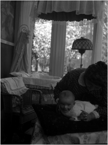 182249 Jo Coovels met één van haar zoontjes : met op de achtergrond de wieg. of Francisca Dijkhof-van Thiel speelt met ...