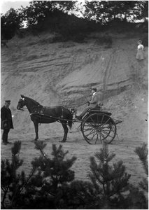 182337 Het rijden in een rijtuig door Jan Smitz, Maria Coovels kijkt boven in de duinen toe, z.j.