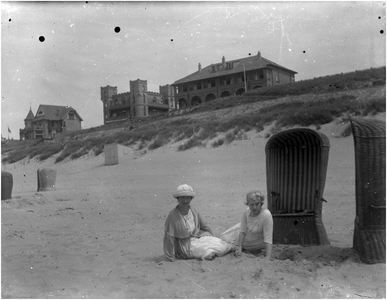 182343 Paula Coovels en Louise Coovels (rechts) zitten op het strand bij strandstoelen, 1920 - 1930