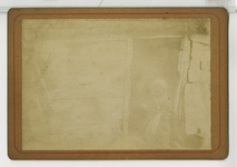 390102 Vrouw met naaiwwerk zittend in deuropening van een houten huis, ca. 1890