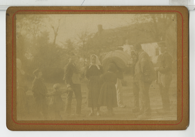 390125 Man met bundel textiel en een groep dorpelingen, ca. 1890