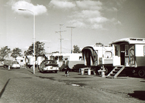 5816 Woonwagens met hun bewoners: vuilnisbakken, hond, auto's en een man zittend op een stoel, 1962