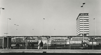 195663 Wachthokjes (abri's), wachtende mensen en bussen aan het busstation, 1970