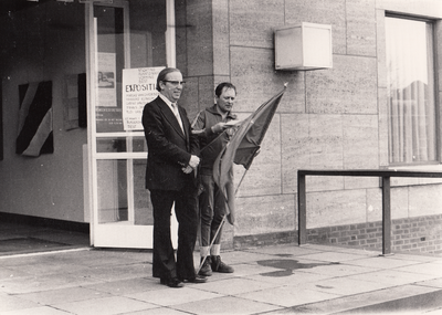 242852 Het overhandigen de vlag aan een deelnemer van de Europamars door de gemeentesecretaris, 04/04/1977