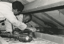 198736 Het verwijderen van een wespennest, op een zolder, door twee mannen met gifspuiten, 30-09-1970