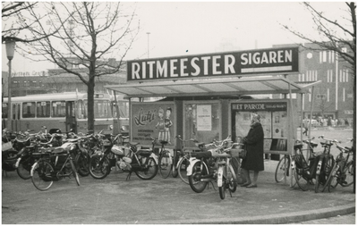 1031 Een fietsenstalling, een wachthuisje bij het busstation op het Stationsplein, richting De Bijenkorf, 1969