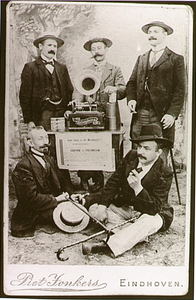 2633 Jan Bijnen: fotograaf (links zittend) en een groepje mannen met een echophone, ofwel spreekmachine, 1895 - 1905