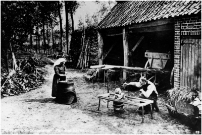9411 Uit de serie Brabantsch Dorpsleven een boerin aan het karnen, de boer speelt met kind in looprek, ca. 1900