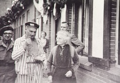 22535 Thuiskomst van pater Van Genuchten uit concentratielkamp Dachau. Rechts zijn moeder, 25-05-1945