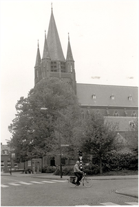 129055 Fietser in de bocht voor de St. Willibrorduskerk, 05-1984