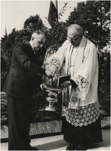 130936 Burgemeester Ras behulpzaam bij een zegening door de priester van de R.K. kerk H. Lambertus, 05-1957