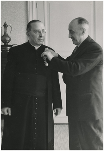 131287 Pastoor H.F.M.J. Bless, onderscheiden in de Orde van Oranje-Nassau door burgemeester A. Ras, 22-04-1955