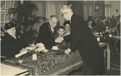 131351 Burgemeester Ras wordt gefeliciteerd door gemeente-secretaris Leo van de Laar, 04-01-1958