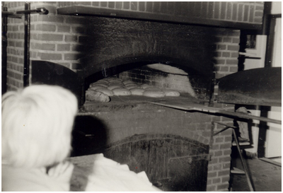 146166 Het in de oven schuiven van de broodjes door de bakker in het bakkerijmuseum De Grenswachter , ca. 1980