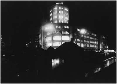 188133 Avondopname van de Philips lichttoren, Mathildelaan, met op de voorgrond enkele woningen en winkels, 1930 - 1935