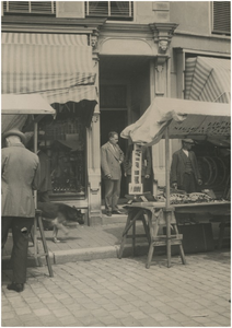 192947 Markt: kramen, een hond en een man staand in een deuropening, ca. 1930