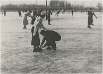 195108 Schaatsen: het recreatief schaatsen, sportpark, Aalsterweg. Man en vrouw, het strikken van een schaatsschoen, 12-1935