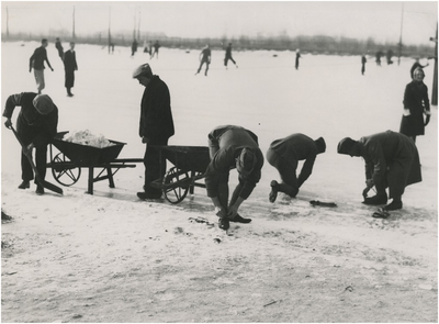 195110 Het onderbinden van de schaatsen en sneeuwvrij maken van de baan, 01-1940