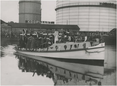 195376 Boot van de Kanaaldienst met Sint Nicolaas en pieten aan boord, op de achtergrond de gashouder, 11-1938