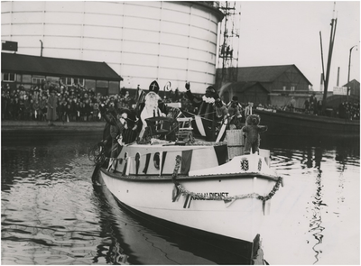 195377 Boot van de Kanaaldienst met Sint Nicolaas en pieten aan boord, op de achtergrond de gashouder, 11-1938