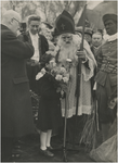 195385 Aankomst St. Nicolaas: Meisje biedt St. Nicolaas bloemen aan, 11-1950