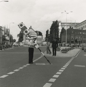 195746 Politieman steekt, op kruispunt, stoplicht in de weg, 1961-1965