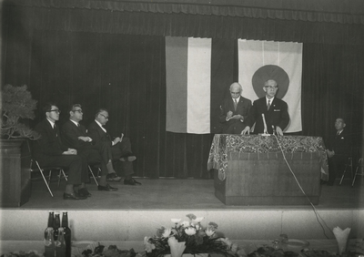198649 Het bijwonen van een toespraak door Mr. K. Matsushita op een podium, naast hem burgemeester Witte en wethouder ...