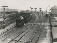 254007 Het vertrekken van een stoomtrein van het station, rechts het stationsgebouw, 1936