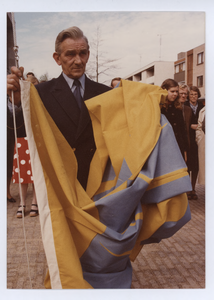 569590 De onthulling van de nieuwe gemeentevlag. Een lid van B & W met de vlag, 03-05-1977