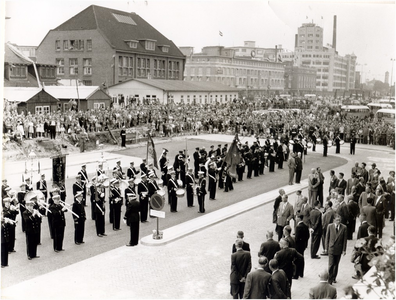 137010 Toeschouwers tijdens het optreden van de harmonie voor het station, rechts de gloeilampen - fabriek van Philips, ...