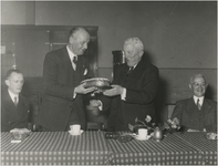 197167 Het aanbieden van een taart door burgemeester Kolfschoten aan oud wethouder P. van der Putt met links naast de ...