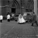 254941 Pastoor met twee acolieten (misdienaar) zegen bromfiets en drie auto voor de Catharinakerk, 05-1955