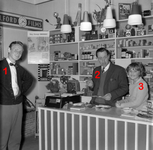 254906 Frans van Mierlo achter de toonbank van zijn winkel met waarschijnlijk zijn dochter en zoon, klok, camera’s met ...
