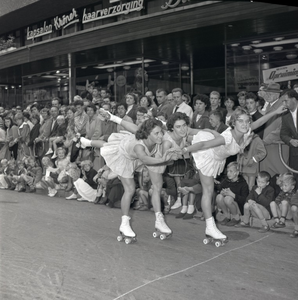 254966 Samenspel van drie rolschaatssters op één been, toeschouwers, 1959