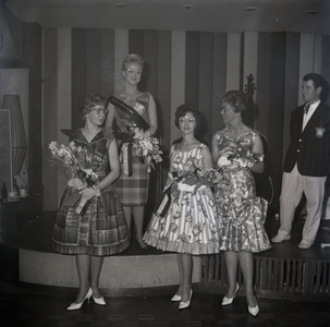 254968 De prijswinnaars, vier dames met bloemen, muzikant op het podium, 1961
