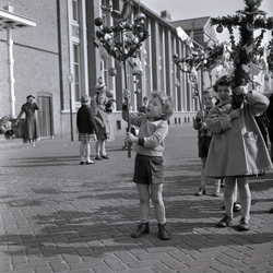 254975 Jongen en meisje met versierde palmpasenstokken, 03-1958